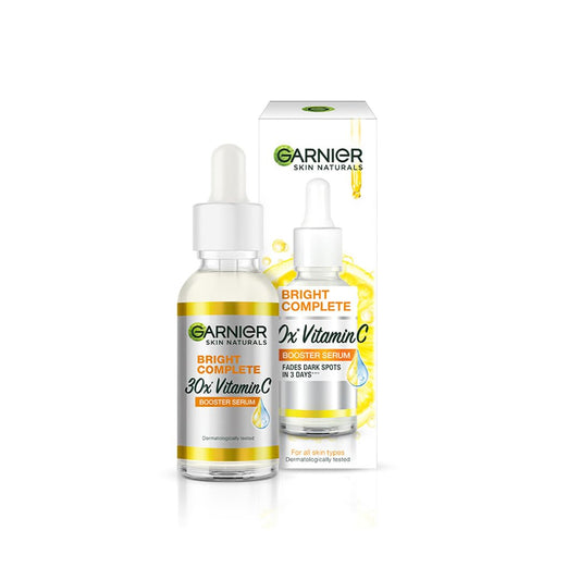 An image of Sparkling Fusion Garnier Skin Naturals Bright Complete 30X Vitamin C Booster Face Serum, a brightening serum for both men and women in a small glass bottle with a dropper cap, next to its white and yellow box packaging. The label states it increases skin's glow instantly, reduces spots over time, and contains 30x Vitamin C along with 2% Niacinamide and 0.5% Salicylic Acid. This comes in a 15 ml size.